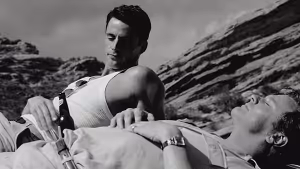 Jim (Matthew Goode) looks down at George (Colin Firth) reclining on a rocky beach