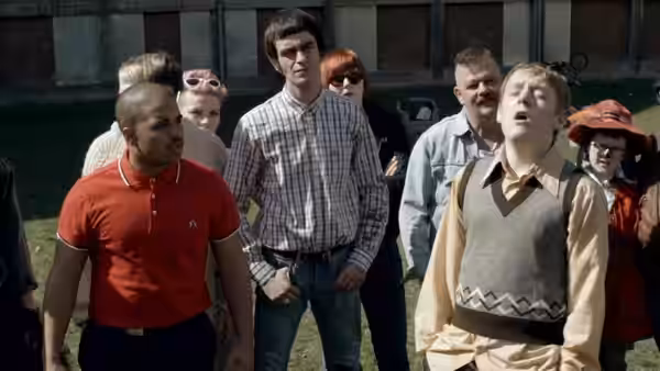Shaun (Thomas Turgoose) standing among a group of people on grass