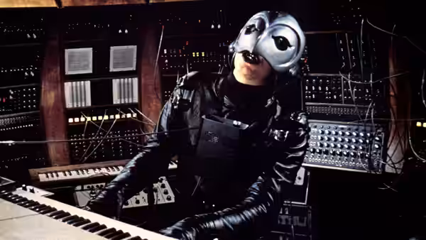 The Phantom playing keyboards in a recording studio control room