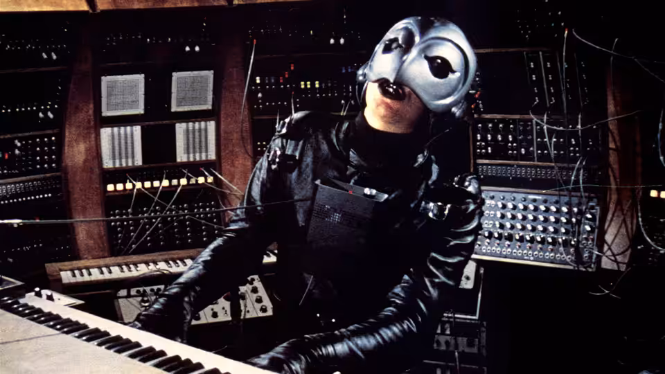 The Phantom playing keyboards in a recording studio control room