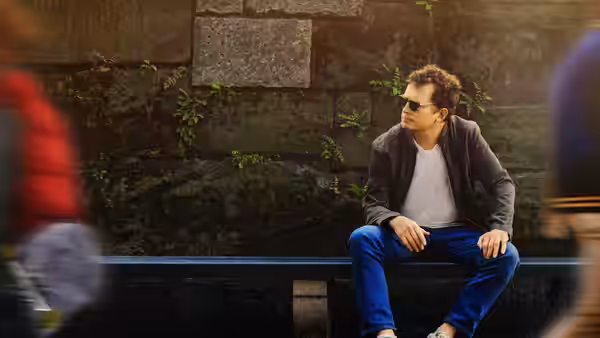 Michael J. Fox (Michael J. Fox) sits on a bench beside a stone wall