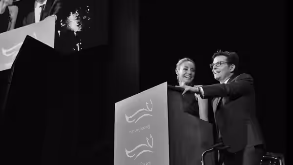 Michael J. Fox and a woman stand behind a podium at a public event