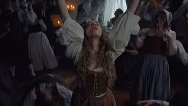 Ann Lee (Amanda Seyfried) raising her arms high in a crowded room