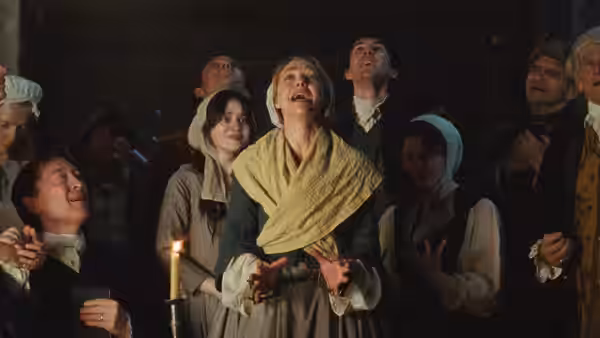 Ann Lee (Amanda Seyfried) with mouth open among a candlelit crowd at night