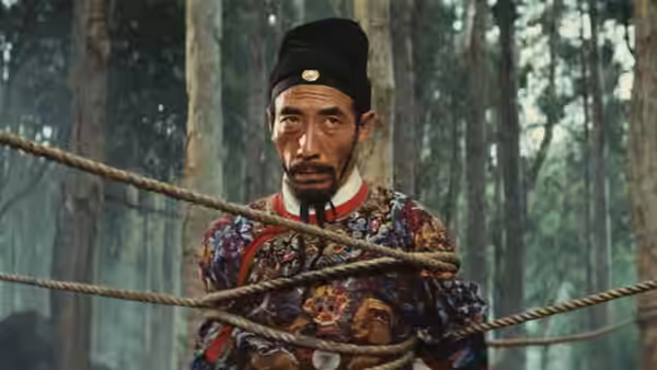 A mustached official in embroidered robes is bound with ropes among the trees