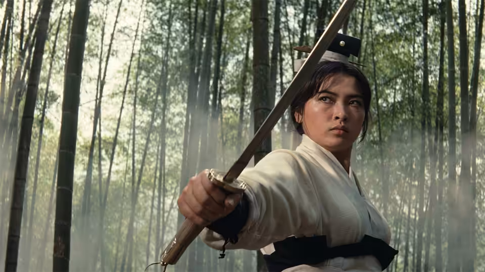 Yang Hui-zhen (Hsu Feng) raises a sword among the trees