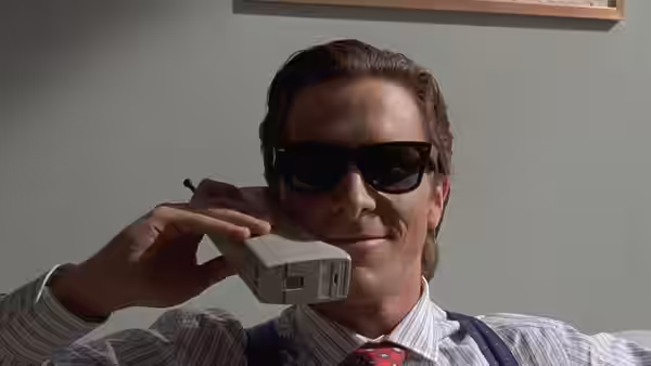 Patrick Bateman (Christian Bale) holding a phone to his ear wearing sunglasses
