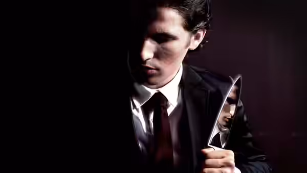 Patrick Bateman (Christian Bale) looking down while holding a knife in a suit