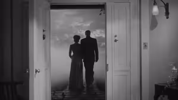 Two figures stand silhouetted in a doorway overlooking the sea