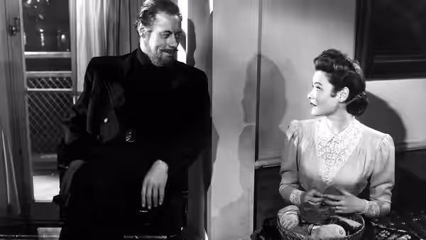 Captain Daniel Gregg (Rex Harrison) watches Lucy Muir (Gene Tierney) seated beside him
