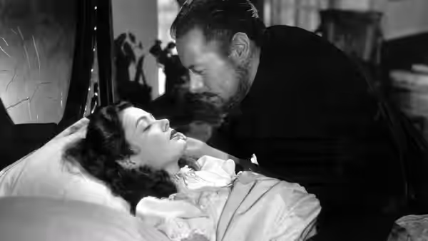A man leans over a woman resting in bed