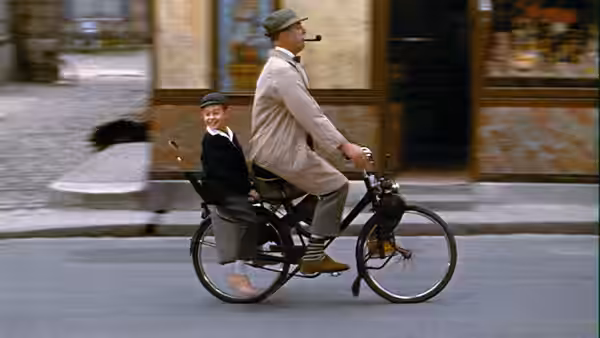 Monsieur Hulot pedals a bicycle with a young boy riding behind him