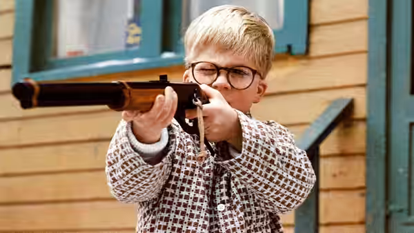 Ralphie (Peter Billingsley) aims a rifle outside a house