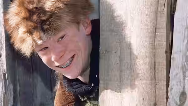Scut Farkus (Zack Ward) grins through a gap in a wooden fence