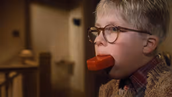 Ralphie (Peter Billingsley) stands indoors with a red soap bar in his mouth