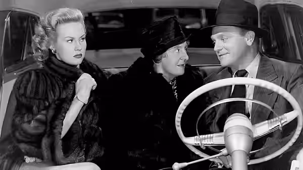 Verna Jarrett (Virginia Mayo) sits beside two men in a car