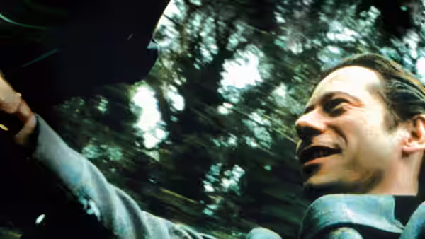 Jean-Dominique Bauby (Mathieu Amalric) smiling while driving a car through a forest