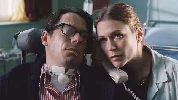 Jean-Dominique Bauby (Mathieu Amalric) reclining in a wheelchair while a woman holds a telephone to his ear