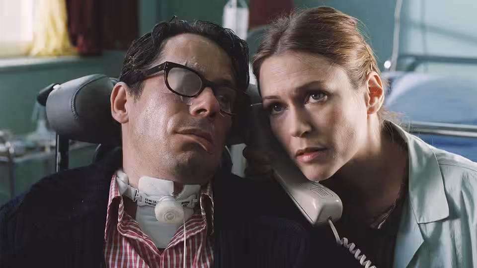 Jean-Dominique Bauby (Mathieu Amalric) reclining in a wheelchair while a woman holds a telephone to his ear