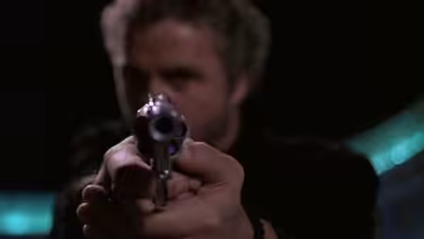 Will Graham (William Petersen) holding a revolver pointed toward the camera in close-up