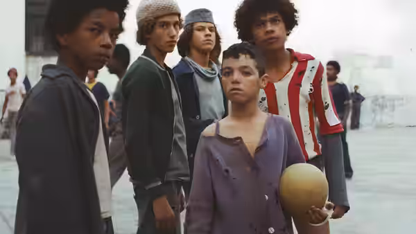 Five boys stand in a line outdoors one holding a ball