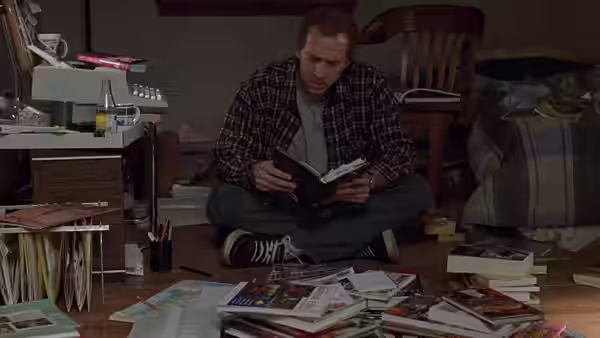 Charlie Kaufman (Nicolas Cage) sitting on the floor reading a book
