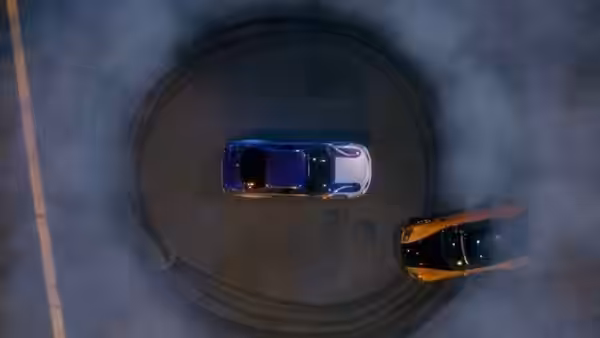 Two cars circle each other in a smoky nighttime race