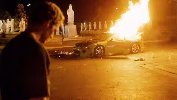 Brian O'Conner (Paul Walker) watches a car engulfed in flames beside a statue-lined plaza