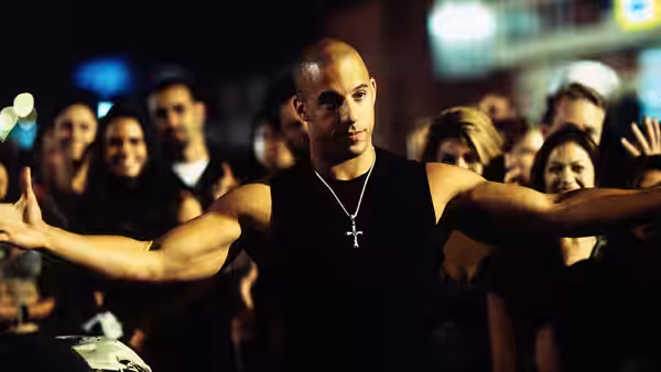 Dominic Toretto (Vin Diesel) spreads his arms before a crowd at a street race