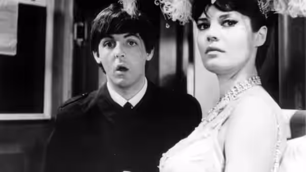 Paul McCartney stands beside a woman in a bright interior