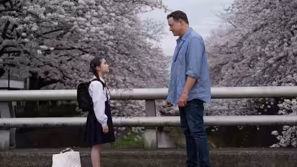 Phillip Vanderploeg (Brendan Fraser) facing a young girl under cherry blossoms