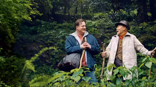 Phillip Vanderploeg (Brendan Fraser) hiking in woods with an older man