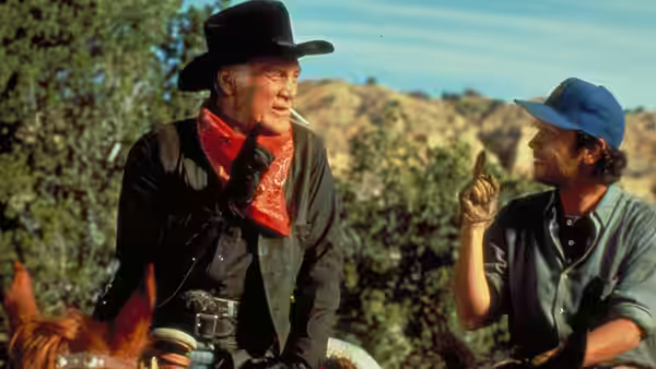 Curly Washburn on horseback talking to a man in a blue cap