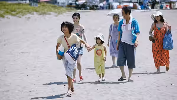 A family group walking together across a wide sandy beach