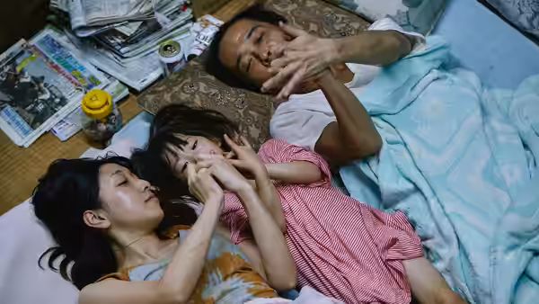 Osamu (Lily Franky) Nobuyo (Sakura Andō) and Yuri (Miyu Sasaki) lying on a futon