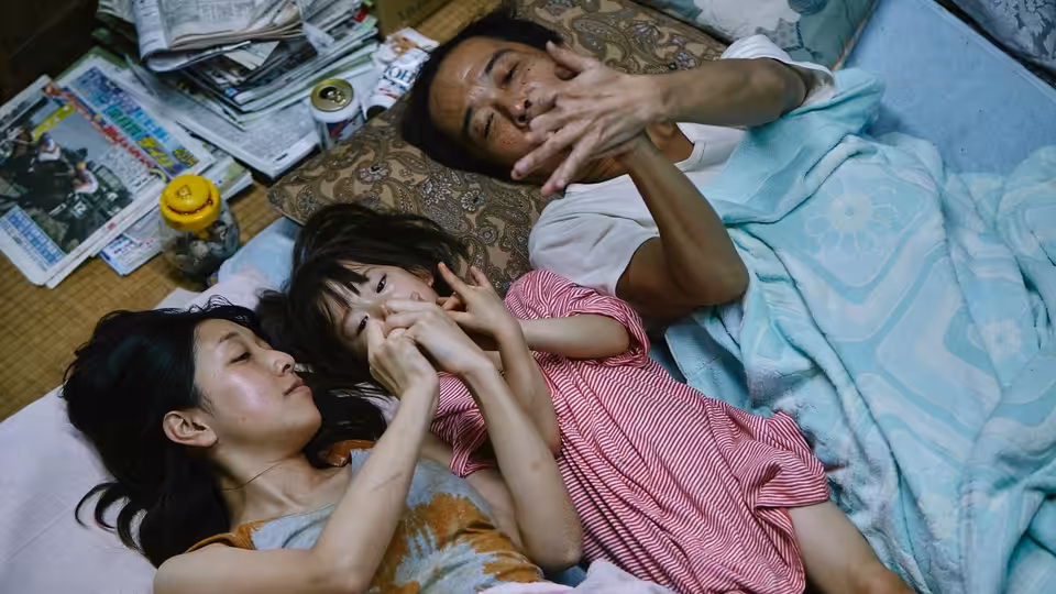 Osamu (Lily Franky) Nobuyo (Sakura Andō) and Yuri (Miyu Sasaki) lying on a futon
