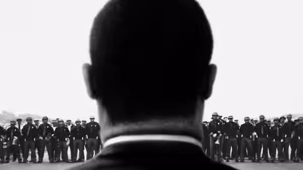 Man facing rows of helmeted police officers standing in formation on pavement