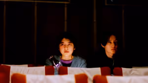 Two women sit together behind rows of empty theater seats