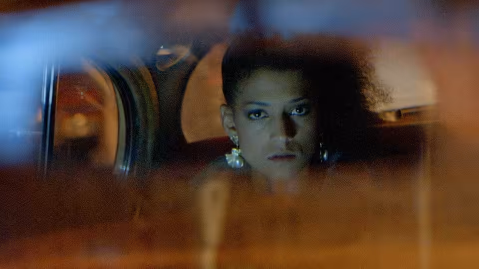 Simone (Cathy Tyson) looking out from the back seat of a car at night