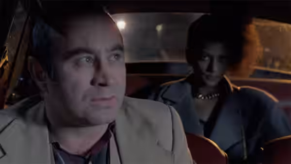 George (Bob Hoskins) in the front seat with Simone (Cathy Tyson) behind him