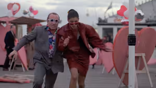 George (Bob Hoskins) and Simone (Cathy Tyson) running past large heart decorations