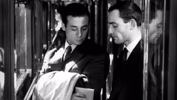 Michel (Martin LaSalle) reaches into a passenger’s coat as another man watches beside him