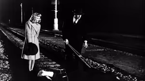 Phyllis Dietrichson (Barbara Stanwyck) and Walter Neff (Fred MacMurray) beside a body on railway tracks