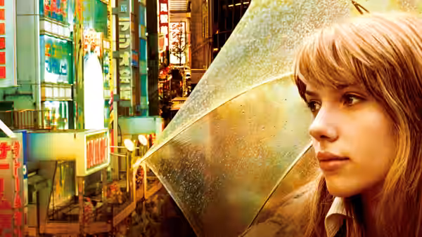 Charlotte (Scarlett Johansson) holding a clear umbrella on a neon-lit street