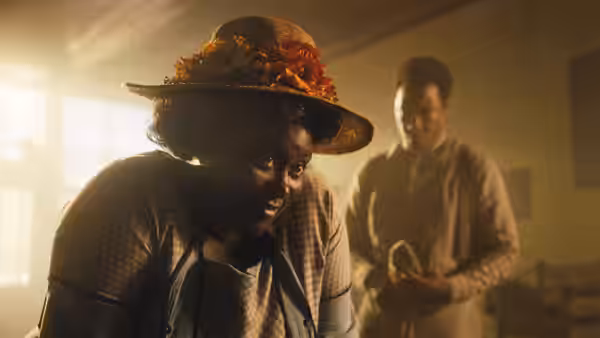 Sofia (Danielle Brooks) leans forward in a sunlit room as a man stands behind her
