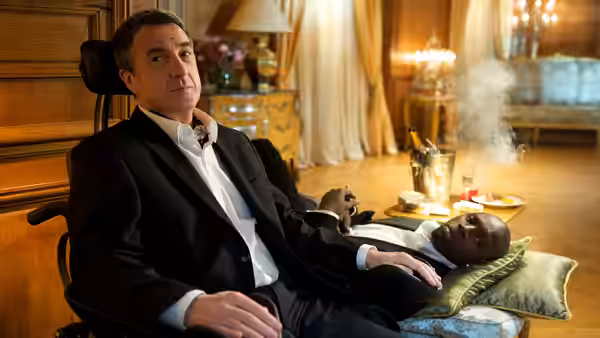 Philippe (François Cluzet) seated beside Driss (Omar Sy) resting on a cushion