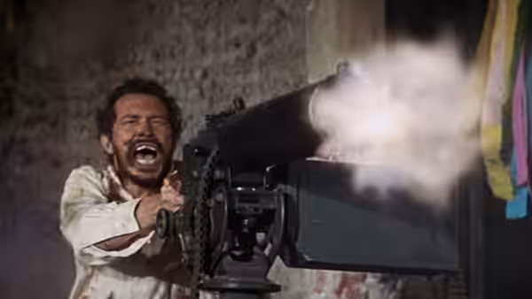 A man fires a mounted machine gun as smoke billows from its barrel