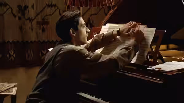Władysław Szpilman (Adrien Brody) reaching across a piano for sheet music