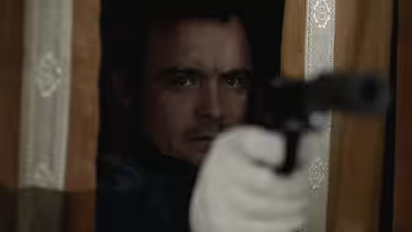 Jay (Neil Maskell) aims pistol from behind curtain