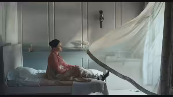 Fanny Brawne (Abbie Cornish) sits on a bed as a sheer curtain billows
